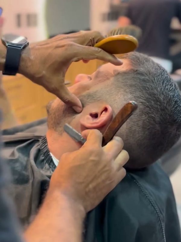 Barbeiro fazendo a barba com navalha