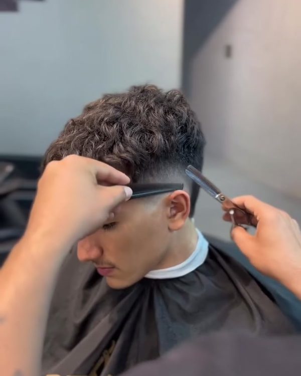 Barbeiro finalizando corte com tesoura e pente